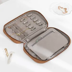 Travel jewelry organizer box, brown leather portable case with compartments for rings and necklaces.