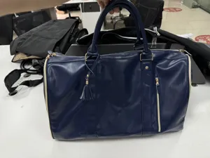 Dark blue PU leather travel duffel bag with front zipper pocket and tassel charm detail.