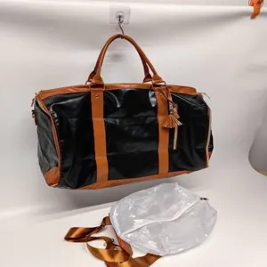 Detail view of black and brown PU leather travel duffel bag with detachable strap.