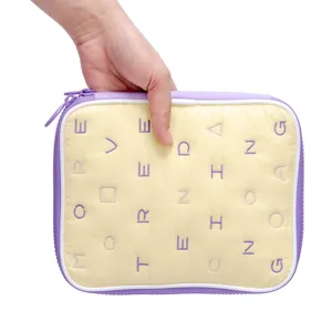 Vue détaillée de sac de rangement d'accessoires numériques matelassé, tissu doux bord violet.