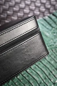 Close-up detail of black leather watch storage box zipper and fine stitching craftsmanship.