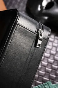 Close-up detail of black leather watch storage box showing zipper and fine texture.