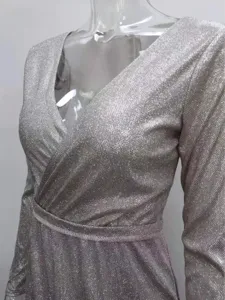 Close-up detail of women's sparkling silver long sleeve V-neck evening dress fabric texture