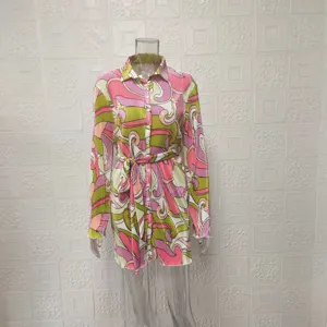 Detailed view of the vibrant abstract patterned pleated shirt dress featuring long sleeves and belt.