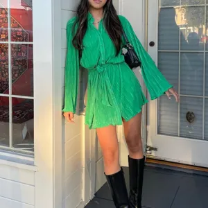 Green long sleeve shirt dress detail, featuring pleated texture, button down and waist belt design.