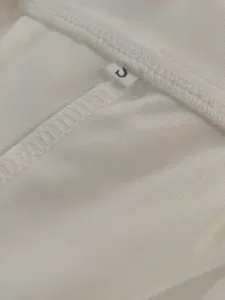 White clothing inner lining detail showcasing fine stitching and a size S label clearly.