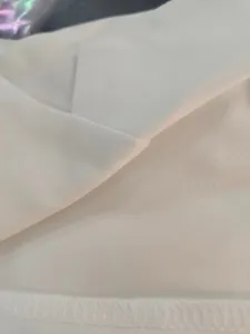 Close-up detail of white suit fabric texture and neat hem stitching for women apparel.