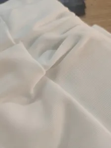 White ribbed fabric texture close-up detail shot, soft and elastic knit material view showing fine lines.
