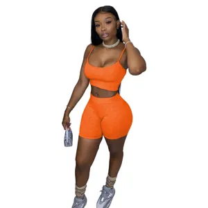 Elegante set da donna con crop top arancione e pantaloncini da biker, perfetto per streetwear.