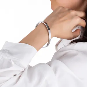 Detailaufnahme eines Edelstahl C-Armreifs, elegant am schlanken Handgelenk getragen.