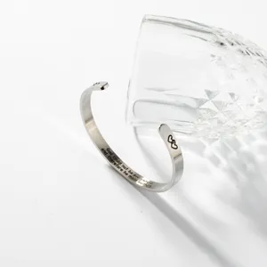 Edelstahl Armreif mit feinen gravierten Textdetails und Glasbecher Dekoration im Detail.