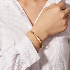 Nahaufnahme eines roségoldenen, gravierten Titanstahl-Armbands im offenen C-Design.