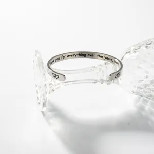 Edelstahl Armreif mit Gravur für Muttertag auf Glas Detailaufnahme stilvoll präsentiert.