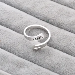 Detailansicht eines modischen offenen Titanstahlrings mit LOVE-Gravur und filigranem Kreuzdesign.
