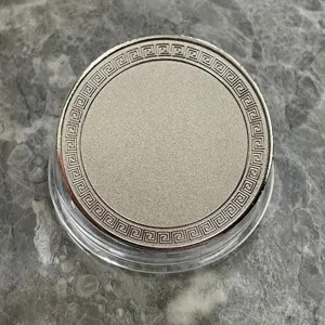 Pièce commémorative vierge avec bordure grecque sous étui transparent pour gravure laser.