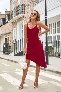 Outdoor street detail shot featuring a red satin cowl neck asymmetric slip dress with side ruches.
