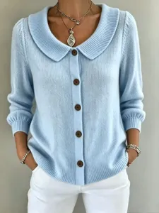 Nahaufnahme des hellblauen Strickcardigans mit Schalkragen und optischen Knopfdetails.