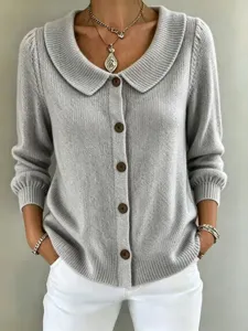 Nahaufnahme der grauen Strickjacke mit Reverskragen und braunen Knöpfen im Detail.
