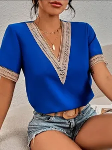 Close-up detail of royal blue short sleeve blouse with elegant beige lace trim V-neck.