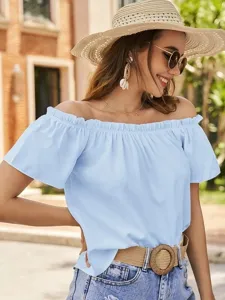 Detailansicht einer hellblauen schulterfreien Rüschenbluse kombiniert mit Denimshorts.
