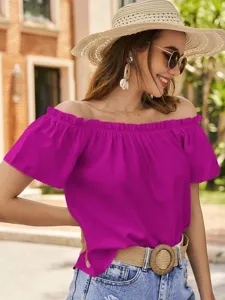 Detailansicht einer leuchtend pinken schulterfreien Rüschenbluse an einem Model im Freien.