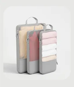 Vista dettagliata dei cubi da viaggio in rete grigia con vestiti organizzati e zip.