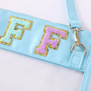 Vue détaillée d'une pochette transparente en TPU avec lettres chenille colorées et fermoirs dorés.
