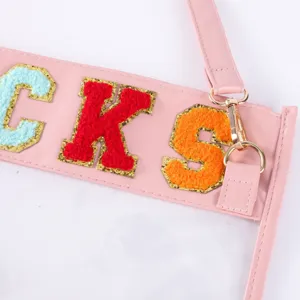 Détail de sac transparent TPU avec patchs de lettres chenille colorées et sangle rose.