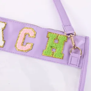 Détail de sac de document TPU transparent avec des patchs de lettres en feutre et sangle violette.