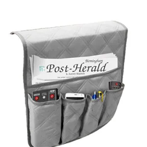 Organizador de reposabrazos de sofá acolchado gris con bolsillos para mandos y móviles.
