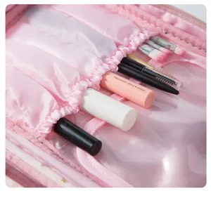 Pink velvet cosmetic bag detail showing elastic brush slots and clear pocket storage.