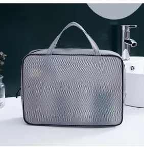 Vista detallada de la bolsa de aseo impermeable de malla gris con textura y asa resistente.