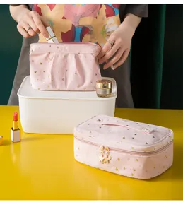 Pink velvet cosmetic bag detail showing gold star patterns, zip closure and portable design.