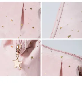 Close up view of pink velvet cosmetic bag featuring gold foil stars and star zipper pull.