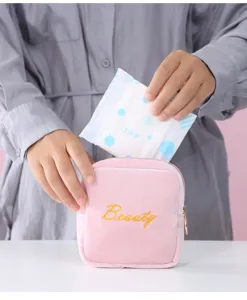 Close-up detail of the pink velvet sanitary napkin pouch showing zipper and embroidery.