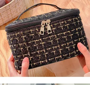 Detailed view of black gold tweed cosmetic bag, featuring convenient handle and metal dual zippers.
