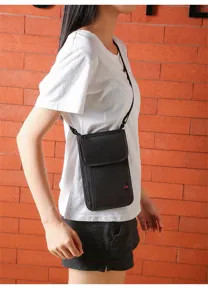 Vue detaillee du sac bandouliere noir impermeable pour passeport porte par le modele en voyage.