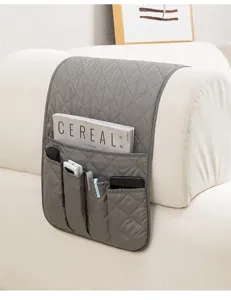 Dettaglio dell'organizer per bracciolo divano grigio trapuntato con tasche multiuso.