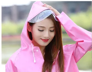 Detalle de impermeable rosa con visera transparente, capucha y cordón para viajes al aire libre.
