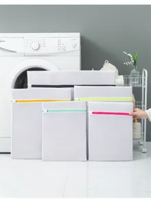 Detail view of white mesh laundry bags with colorful zippers in a clean home laundry room.