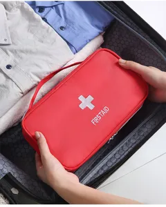 Portable travel emergency first aid bag detail view in suitcase, red medical storage pouch.