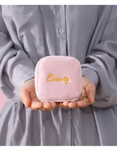 Close-up of pink velvet cosmetic pouch with gold embroidery detail, portable mini storage bag.