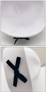 Close-up detail view of white sailor hat interior seams and black velvet bow ornament.