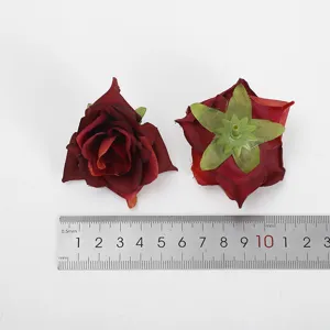 Gedetailleerd uitzicht van kunstmatig rood rozenhoofd met groene kelkblad naast meetliniaal.