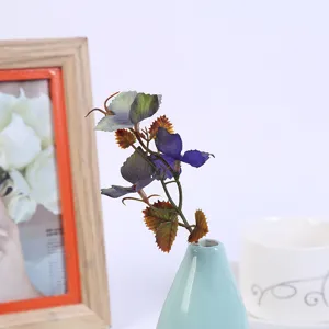 Colorful artificial leaves branch in ceramic vase home decor table arrangement detail shot