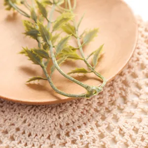 Detailed view of artificial green leaf branch on wooden plate for home decoration and display.