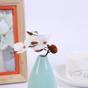 Artificial flower branch in ceramic vase, home decor floral arrangement for living room table.