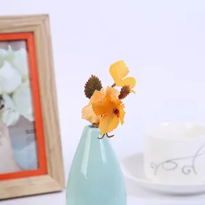 Artificial flower detail view, small yellow floral arrangement in a light blue ceramic vase.