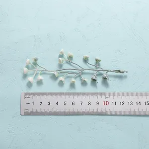 Close-up detail view of artificial greenery branch with cute buds and measurement ruler.