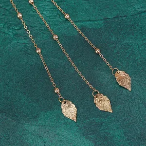 Golden metal tassel chain with leaf pendants, delicate hair accessory decoration detail shot.